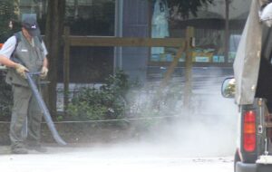 A gas powered leaf blower blowing dust around