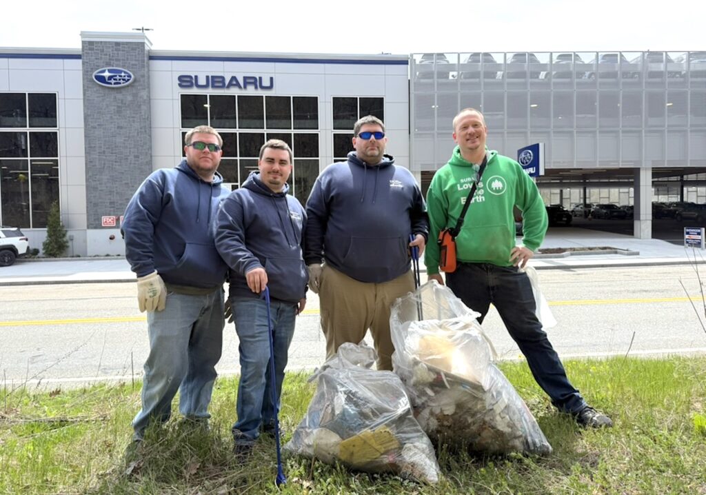 Four men stand with bags of trash they collected at Lone Tree Hill