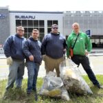 Four men stand with bags of trash they collected at Lone Tree Hill