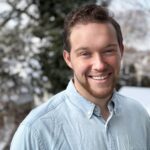 Young white man with a light beard smiling to the camera