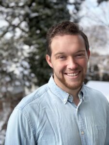 Young white man with a light beard smiling to the camera